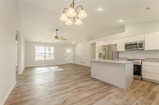 kitchen featuring white cabinets, vaulted ceiling, decorative light fixtures, light hardwood / wood-style floors, and stainless steel appliances