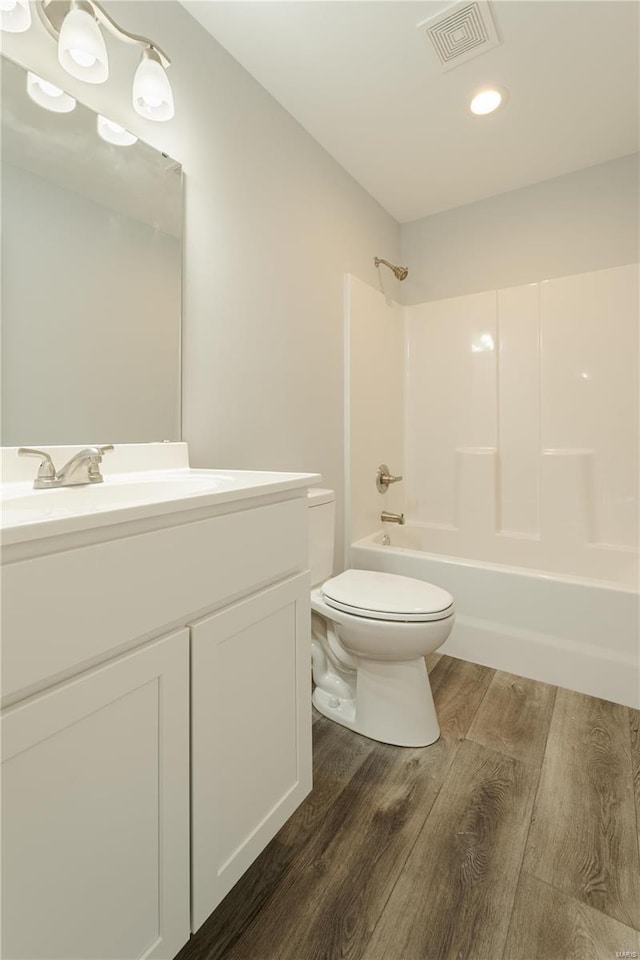 full bathroom featuring hardwood / wood-style floors, vanity, toilet, and tub / shower combination