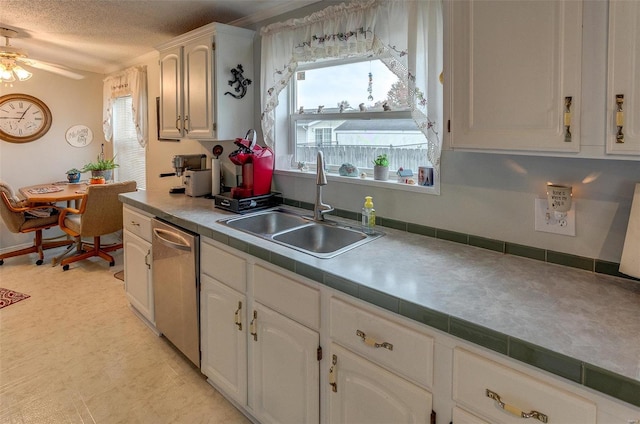 kitchen featuring stainless steel dishwasher, a textured ceiling, ceiling fan, sink, and white cabinets