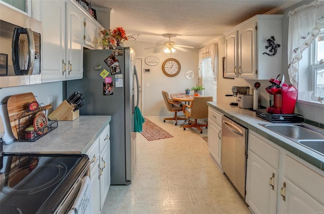 kitchen featuring ceiling fan, white cabinets, a textured ceiling, and appliances with stainless steel finishes