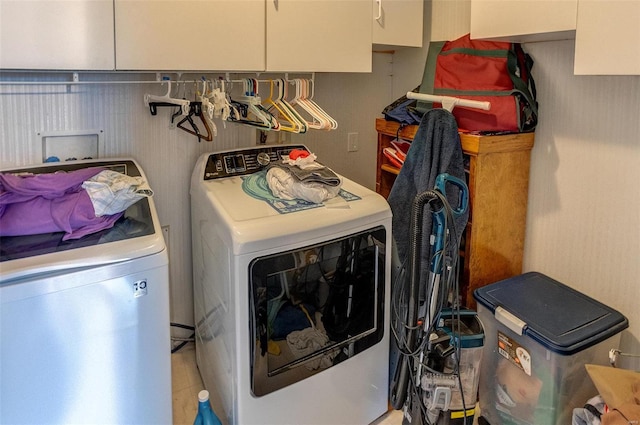 laundry room with washing machine and clothes dryer and cabinets