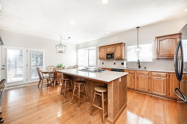 kitchen with a center island, sink, light wood-type flooring, and hanging light fixtures