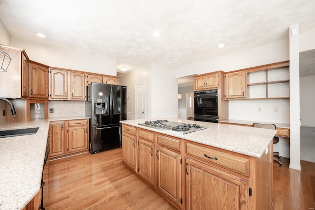 kitchen featuring black appliances, a kitchen island, sink, and light hardwood / wood-style flooring