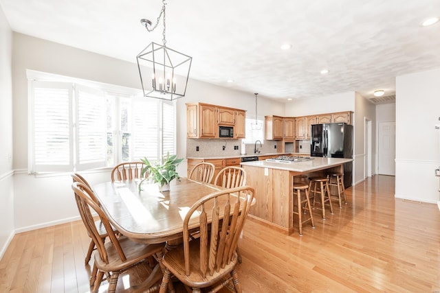 dining area with light hardwood / wood-style flooring, a chandelier, and sink