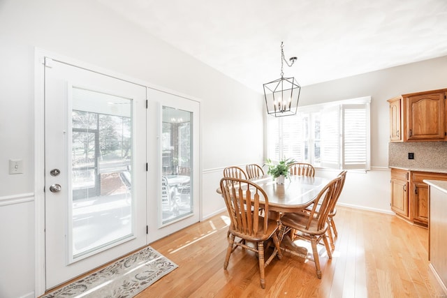 dining room with a notable chandelier, plenty of natural light, and light hardwood / wood-style flooring