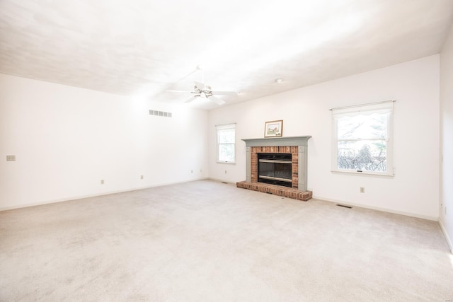 unfurnished living room with light colored carpet, a brick fireplace, and a healthy amount of sunlight