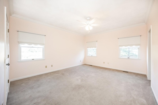 carpeted empty room with a wealth of natural light, crown molding, and ceiling fan