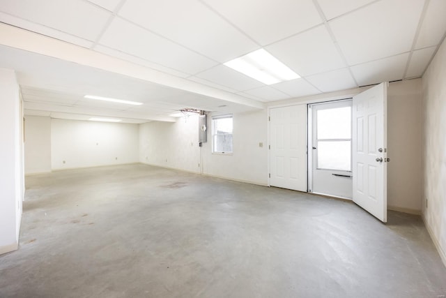 basement with a paneled ceiling and electric panel