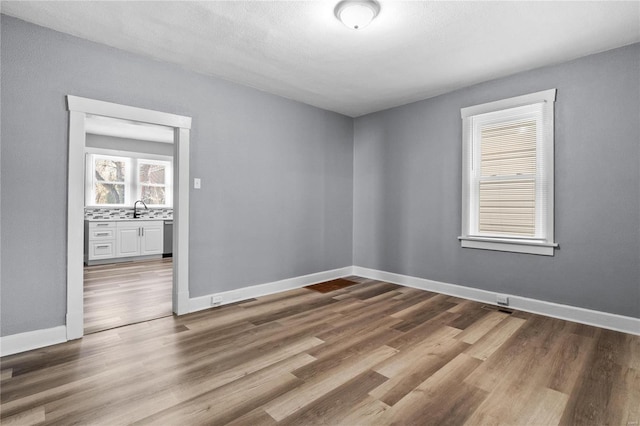 unfurnished room featuring hardwood / wood-style floors and sink