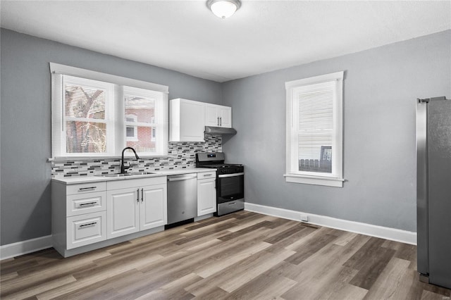 kitchen featuring appliances with stainless steel finishes, light wood-type flooring, backsplash, and sink