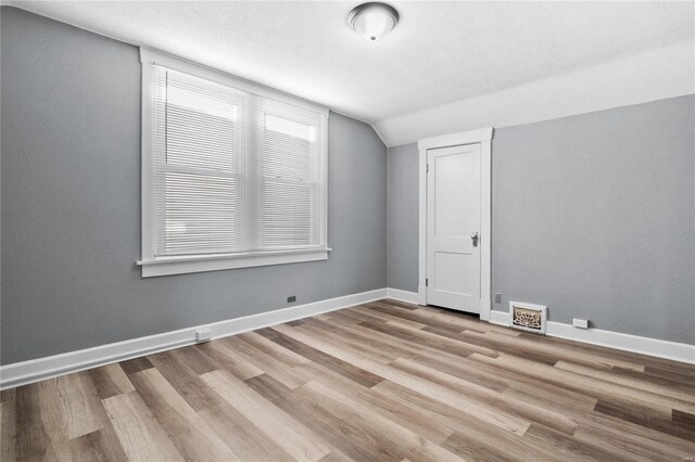 bonus room with lofted ceiling and light wood-type flooring