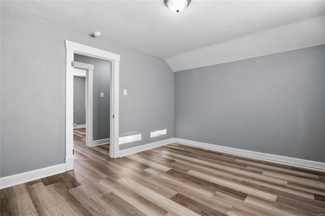 bonus room with hardwood / wood-style floors, a textured ceiling, and vaulted ceiling