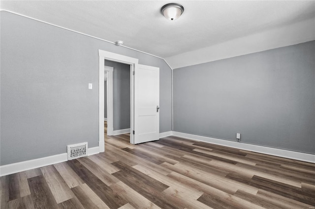 unfurnished room with dark hardwood / wood-style floors and vaulted ceiling