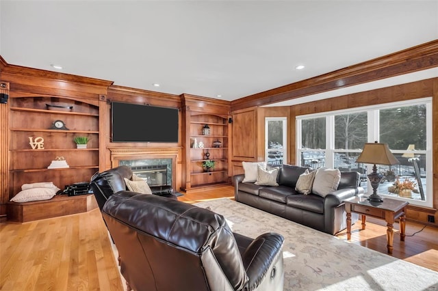 living room with light wood-type flooring, a wealth of natural light, a high end fireplace, and built in features