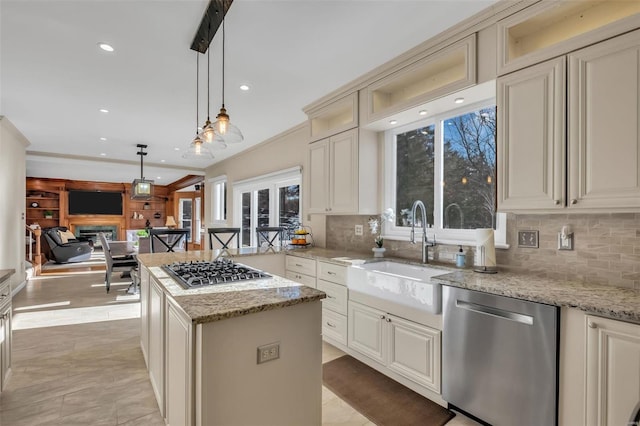 kitchen featuring appliances with stainless steel finishes, a center island, hanging light fixtures, ornamental molding, and light stone counters