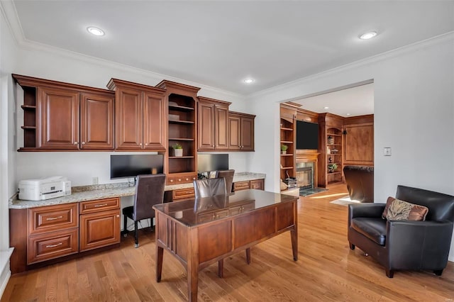 home office featuring ornamental molding, built in desk, and light hardwood / wood-style flooring