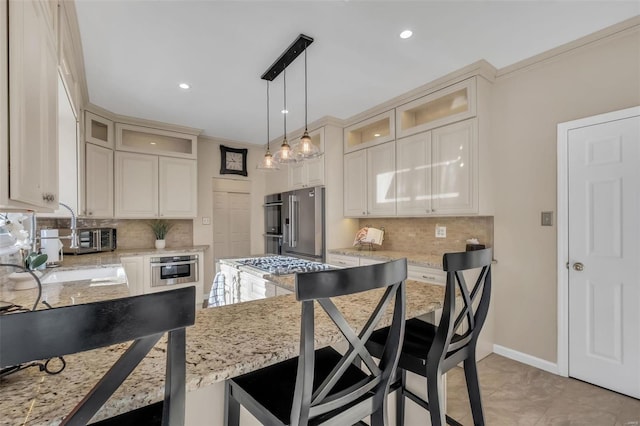 kitchen with pendant lighting, appliances with stainless steel finishes, tasteful backsplash, light stone counters, and a breakfast bar area