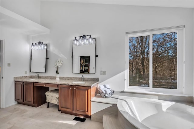 bathroom featuring a tub, plenty of natural light, vanity, and vaulted ceiling