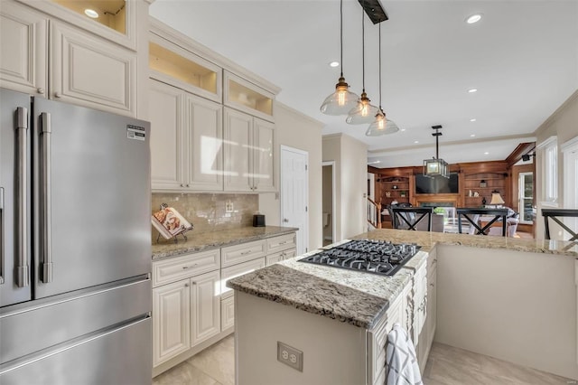 kitchen featuring stainless steel appliances, decorative backsplash, light stone counters, and a kitchen island