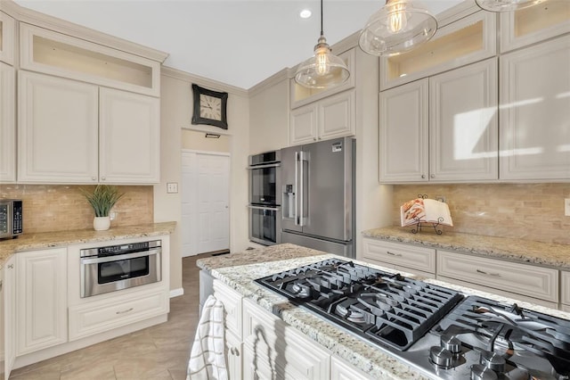 kitchen featuring light stone countertops, appliances with stainless steel finishes, backsplash, and decorative light fixtures