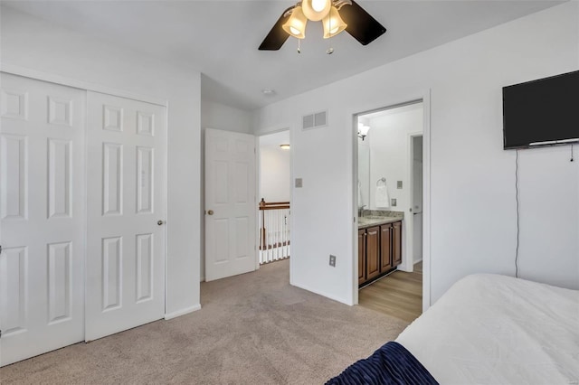 carpeted bedroom featuring ceiling fan, ensuite bathroom, and a closet