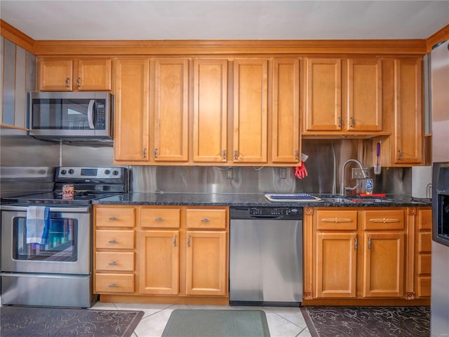 kitchen with sink, backsplash, dark stone counters, light tile patterned floors, and appliances with stainless steel finishes