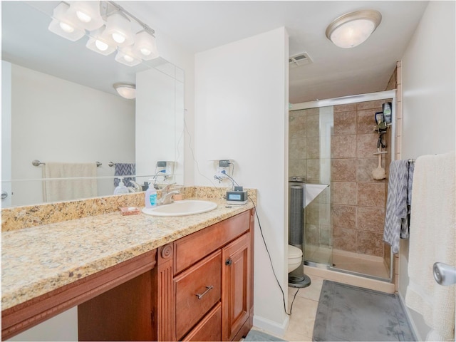 bathroom with tile patterned floors, vanity, toilet, and a shower with shower door