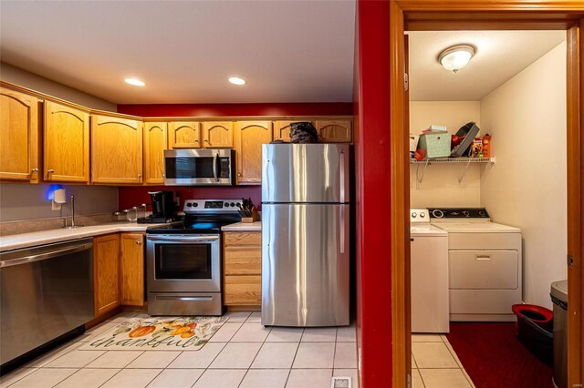 kitchen featuring washing machine and clothes dryer, light tile patterned flooring, and stainless steel appliances