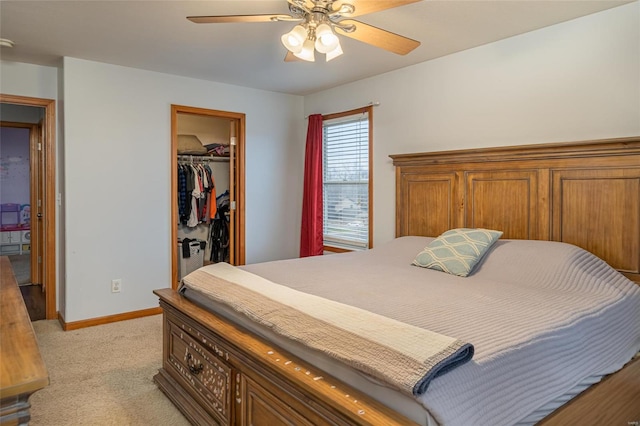 bedroom featuring a walk in closet, ceiling fan, a closet, and light carpet