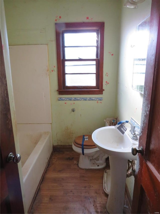 bathroom featuring hardwood / wood-style floors, toilet, and a bath