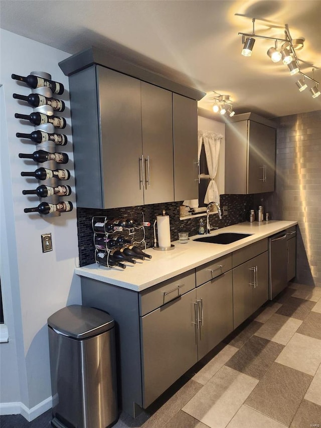 kitchen with tasteful backsplash, gray cabinetry, dishwasher, and sink