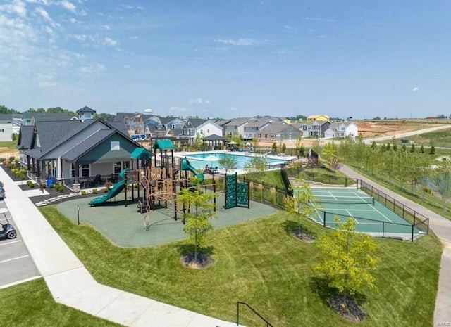 view of playground featuring a lawn and tennis court