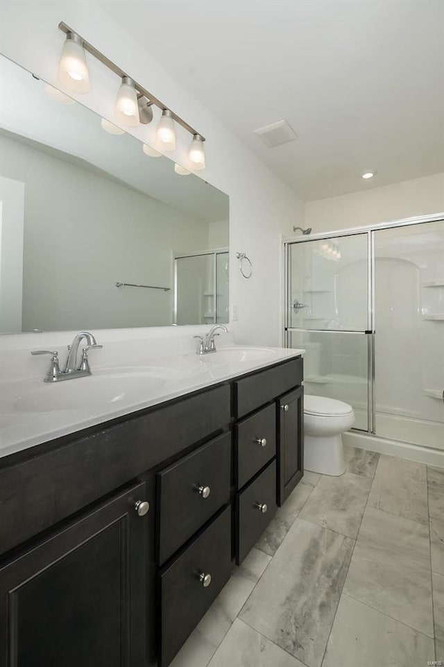 bathroom with a shower with door, vanity, and toilet