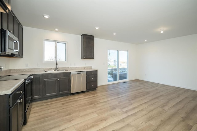 kitchen with appliances with stainless steel finishes, light hardwood / wood-style flooring, and sink