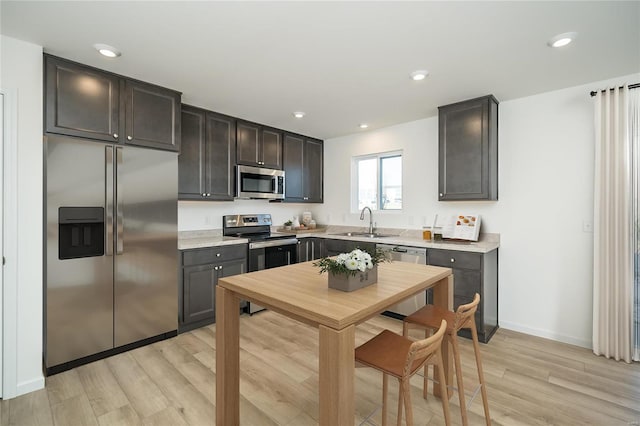 kitchen featuring appliances with stainless steel finishes, dark brown cabinetry, light hardwood / wood-style flooring, and sink