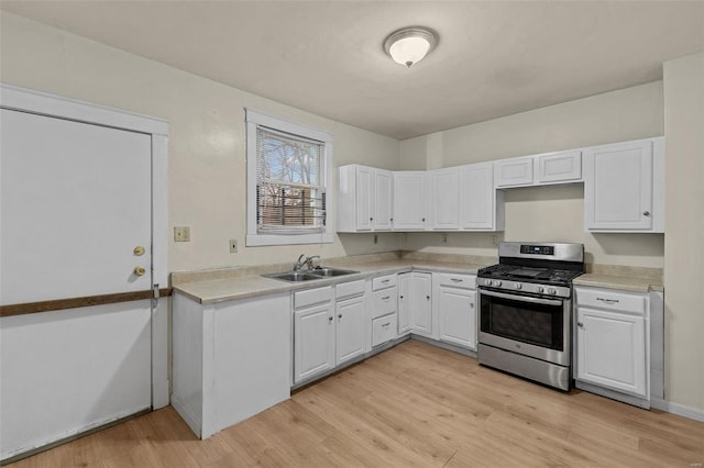 kitchen with white cabinets, stainless steel gas stove, light hardwood / wood-style floors, and sink