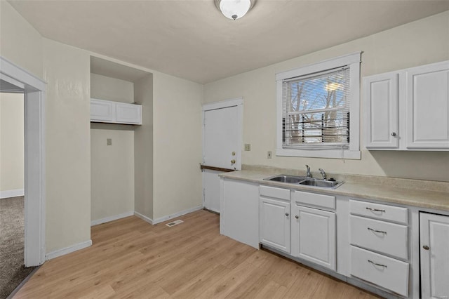 kitchen with sink, white cabinets, and light hardwood / wood-style flooring