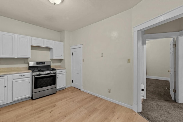 kitchen with gas range, light wood-type flooring, and white cabinetry