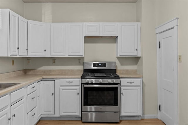 kitchen featuring stainless steel gas range oven, light hardwood / wood-style flooring, and white cabinets