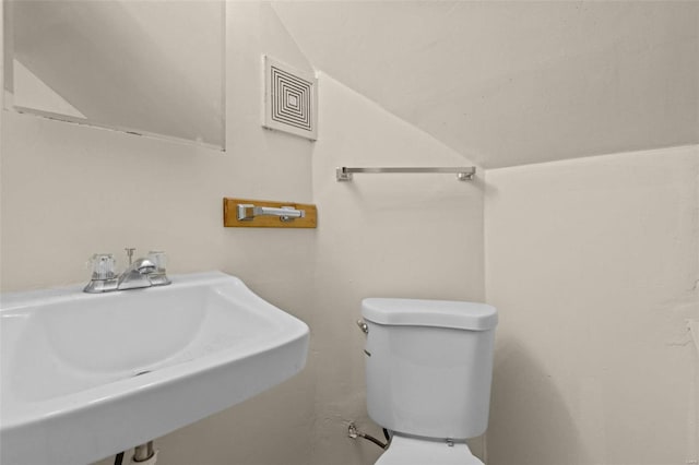 bathroom featuring sink, vaulted ceiling, and toilet