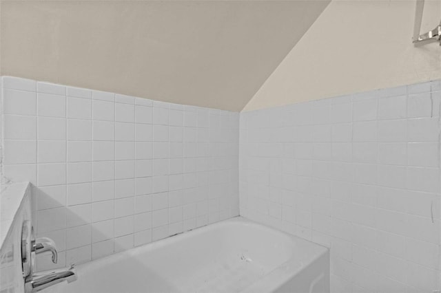 bathroom featuring lofted ceiling and a bath