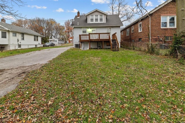 rear view of property featuring a lawn and a deck