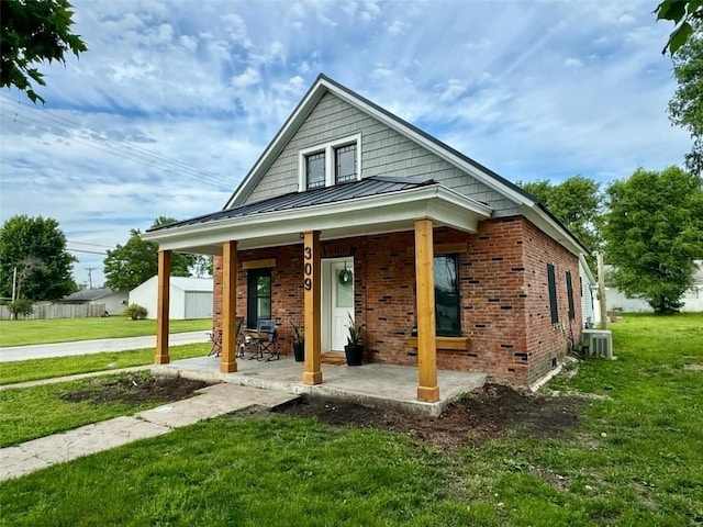 view of front facade with covered porch, a front yard, and central AC