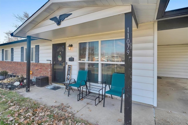 entrance to property with a patio area, brick siding, and fence