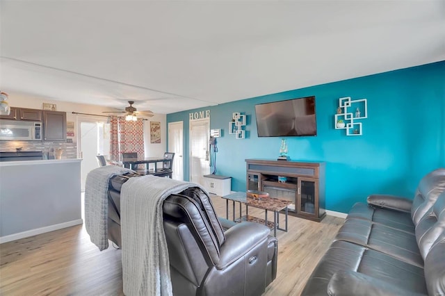 living area with ceiling fan, light wood-type flooring, and baseboards