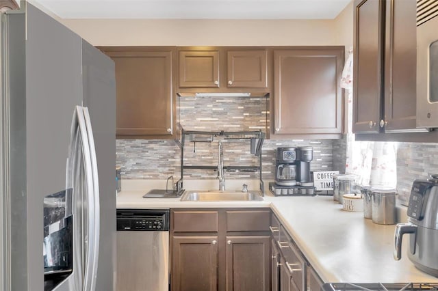 kitchen featuring a sink, stainless steel appliances, decorative backsplash, and light countertops