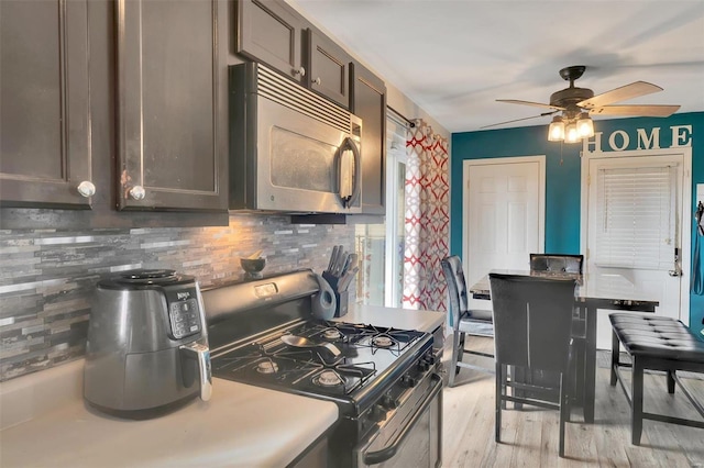 kitchen featuring light wood-type flooring, dark brown cabinetry, light countertops, range with gas cooktop, and tasteful backsplash