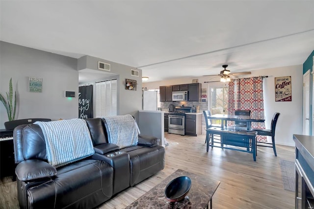 living room with light wood-type flooring, visible vents, baseboards, and a ceiling fan