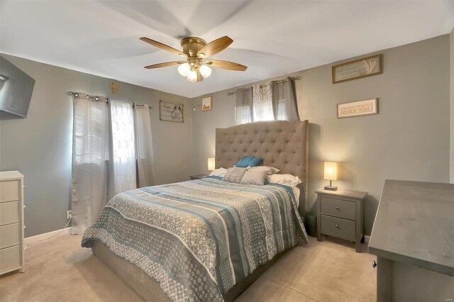 bedroom with baseboards, multiple windows, light colored carpet, and ceiling fan