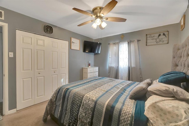 bedroom with a closet, light colored carpet, and a ceiling fan